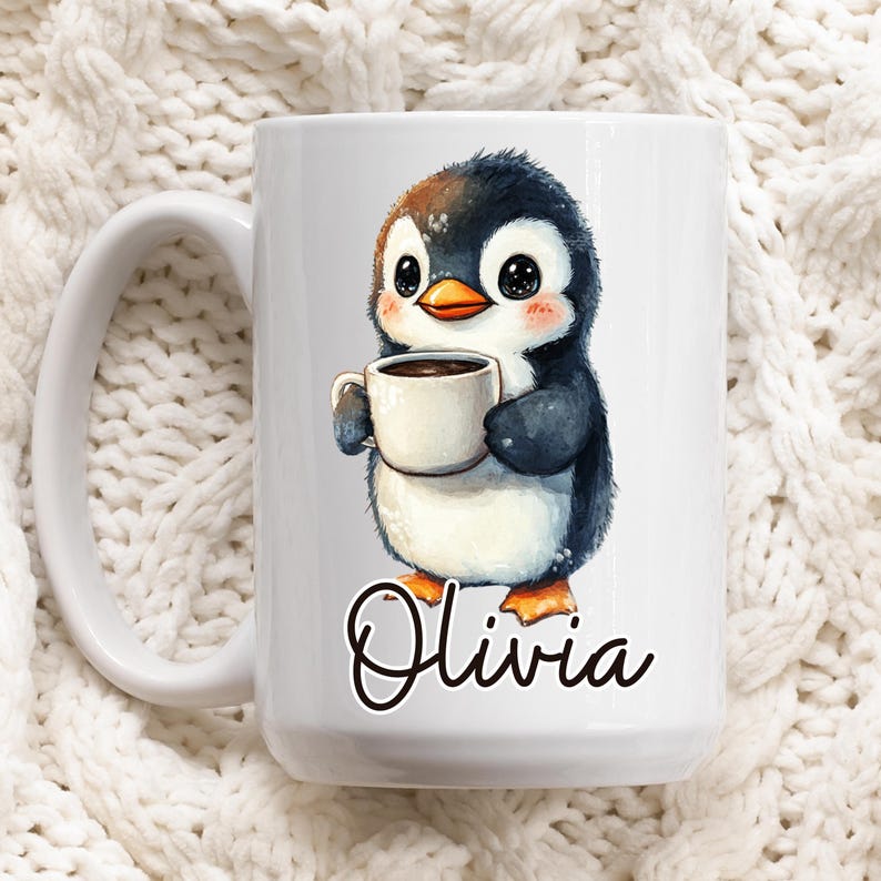 May include: White ceramic mug featuring a watercolor illustration of a cute penguin holding a cup of coffee. The penguin has black, white, and brown feathers, with an orange beak and feet. The name "Olivia" is written in cursive below the penguin.