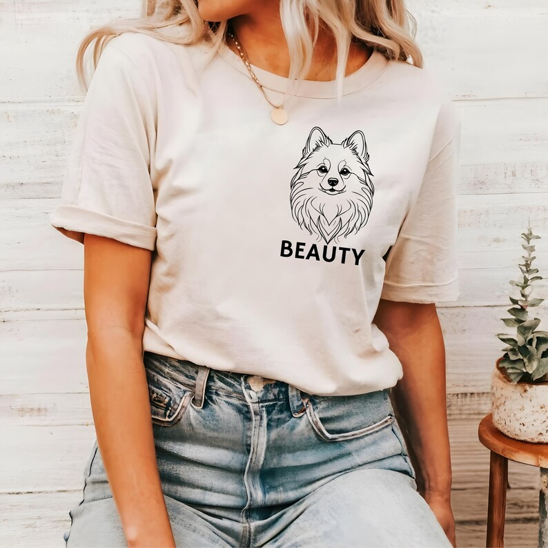May include: A white t-shirt with a black line drawing of a dog's head and the word "BEAUTY" printed on the front.