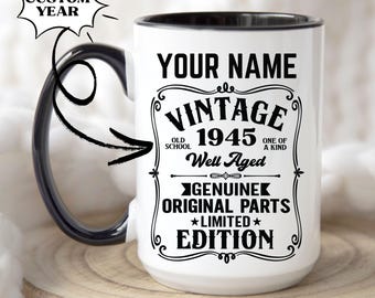 Puede incluir: Taza de café de cerámica blanca con borde y asa negros. La taza tiene un diseño vintage con el texto "YOUR NAME VINTAGE 1945 OLD SCHOOL ONE OF A KIND Well Aged GENUINE ORIGINAL PARTS ★LIMITED★ EDITION".
