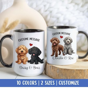 May include: Two white ceramic mugs with black handles and black rims. Each mug features a custom message, a red heart, and a cartoon illustration of two dogs. The mug on the left has the text "Daisy & Bear" and the mug on the right has the text "Charlie & Rex".