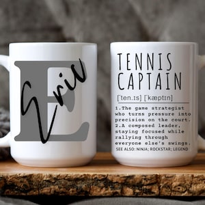 May include: White ceramic coffee mug with a gray letter E and the word "Eril" written in black cursive. The other side of the mug has the words "Tennis Captain" with a definition and the words "Ninja, Rockstar, Legend".