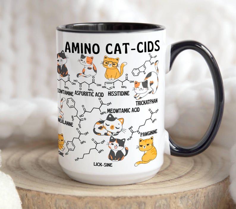 Może przedstawiać: Biały kubek ceramiczny z czarnym uchwytem. Kubek ma grafikę kota z wzorem chemicznym i tekstem "AMINO CAT-CIDS". Grafika zawiera tekst "LICK-SINE", "MEOWTAMIC ACID", "TRICKATPHAN", "PAWGININE", "HISSITIDINE", "CONTAMINE ASPURRTIC ACID" i "NEALANINE".
