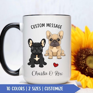 May include: White ceramic coffee mug with a black rim and handle. The mug features a cartoon image of two French Bulldogs, one black and one tan, with the text "CUSTOM MESSAGE" above them and "Charlie & Rex" below them. A red heart is between the dogs.
