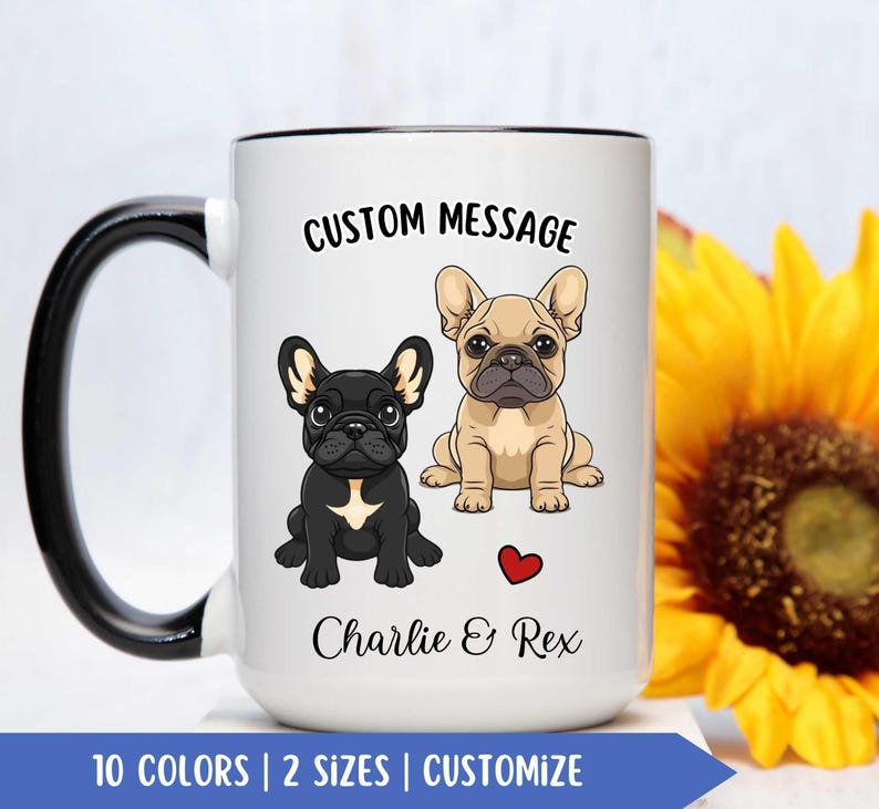 May include: White ceramic coffee mug with a black rim and handle. The mug features a cartoon image of two French Bulldogs, one black and one tan, with the text "CUSTOM MESSAGE" above them and "Charlie & Rex" below them. A red heart is between the dogs.