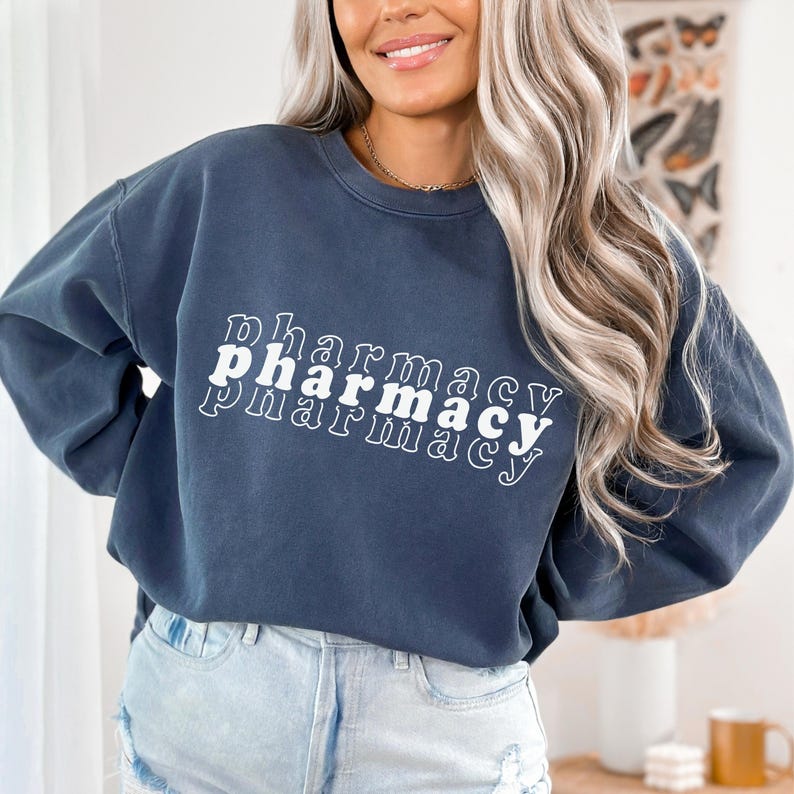 May include: A dark blue sweatshirt with the word "pharmacy" written in white, repeated three times in a layered, retro style.