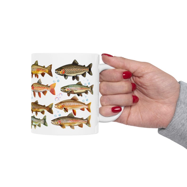 May include: White ceramic mug featuring illustrations of various fish species. The fish are depicted in a detailed, vintage style, with a range of colors including brown, orange, and green. Bubbles are also included in the design.