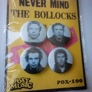 May include: Four round button badges featuring black and white photos of the punk rock band The Sex Pistols. The badges are on a yellow background with the text "Never Mind The Bollocks" and "POX-100".