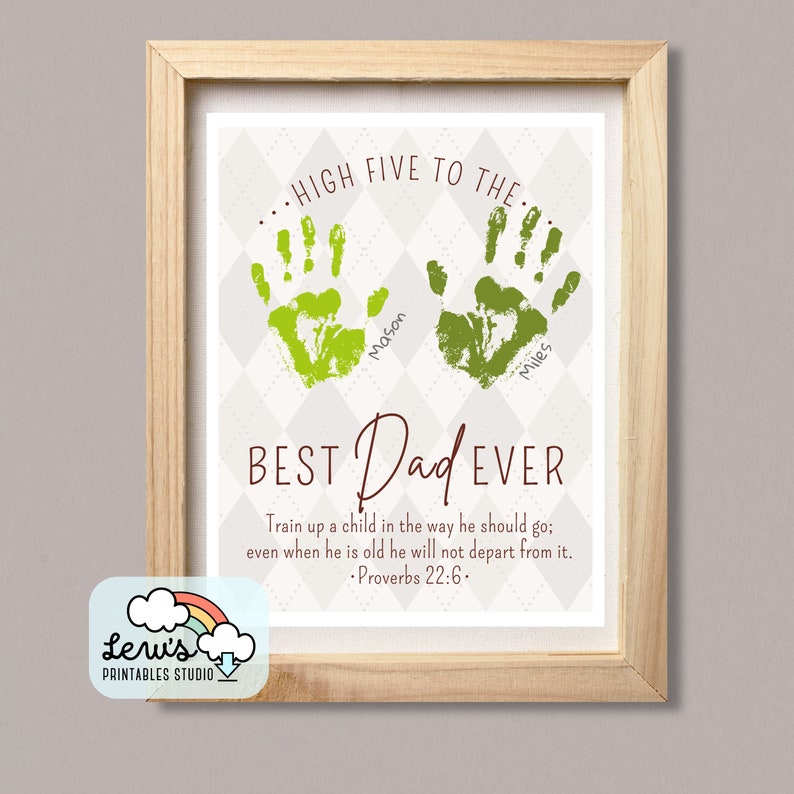 May include: A framed print with a light grey background and a diamond pattern. The print features two green handprints with the names "Mason" and "Miles" written underneath. The text "HIGH FIVE TO THE" is above the handprints and the text "BEST Dad EVER" is below the handprints. The print also includes the text "Train up a child in the way he should go; even when he is old he will not depart from it. - Proverbs 22:6."