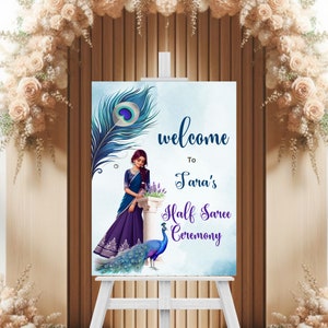 May include: Welcome to Sara's Half Saree Ceremony sign featuring a blue and green peacock feather design and a woman in a purple and blue saree standing next to a peacock.