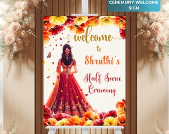 May include: Welcome sign for a half saree ceremony with a floral design and a woman in a red and gold saree. The sign says "Welcome to Shruthi's Half Saree Ceremony".