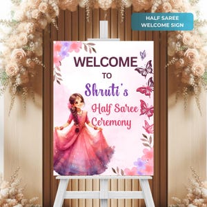 May include: Welcome sign for a half saree ceremony with a pink watercolor background, butterflies, and a cartoon illustration of a girl in a pink saree. The sign reads "Welcome to Shruti's Half Saree Ceremony".