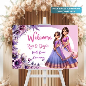 May include: Welcome sign for a half saree ceremony featuring a floral design and two girls in traditional Indian dress. The sign reads "Welcome Riya & Diya's Half Saree Ceremony".
