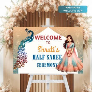 May include: Welcome sign for a half saree ceremony with a peacock design and a girl in a pink and blue saree. The sign says "Welcome to Shruti's Half Saree Ceremony".