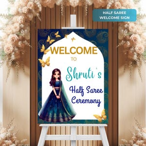 May include: Welcome sign for a half saree ceremony with a blue and gold paisley design. The sign features a cartoon illustration of a girl in a blue and green saree with gold accents. The text on the sign reads "Welcome to Shruti's Half Saree Ceremony".