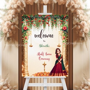 May include: A decorative welcome sign for a Half Saree Ceremony, with floral and gold detailing. The sign reads "welcome to Shruti" and includes a cartoon illustration of a woman in a saree. The sign is displayed on a white easel.