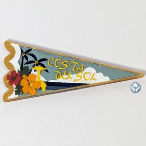 May include: A triangular pennant-shaped decorative item with the words "COSTA DEL SOL" in yellow. The design includes palm trees, flowers, and a boat, with a gold glitter border. The background is a light blue color.