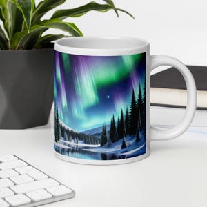 May include: White ceramic mug with a colorful image of the aurora borealis over a snowy forest. The aurora is green, purple, and blue, and the forest is silhouetted against the night sky.