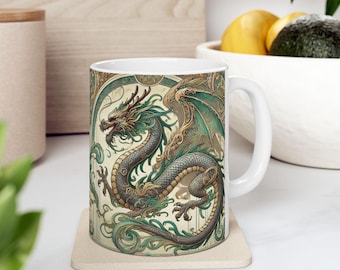 May include: White ceramic mug featuring a green and gold dragon design. The dragon is depicted in a stylised, intricate design with swirling patterns and details. The mug has a handle on the right side.