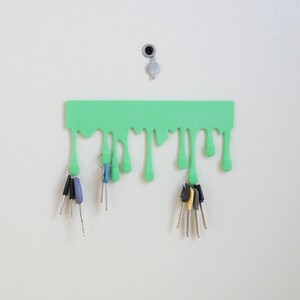 May include: A green key holder shaped like dripping slime with multiple keys hanging from it.