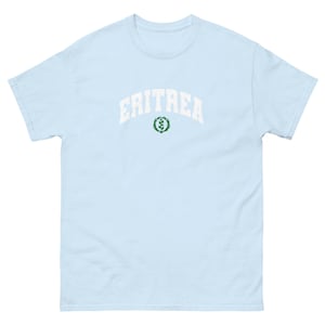 May include: Light blue t-shirt with white text that reads "ERITREA" in an arched font. A green wreath with a small plant inside is below the text.