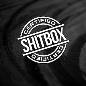 May include: A white circle with the text "CERTIFIED" and "SHITBOX" inside. The text is in a bold, sans-serif font.