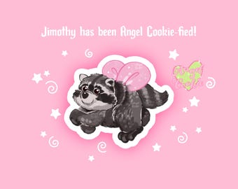 May include: A sticker featuring a grey and black raccoon with pink heart-shaped wings on a light pink background. The text reads Jimothy has been Angel Cookie-fied! and Angel Cookie. White stars and swirls surround the raccoon on the pink surface.