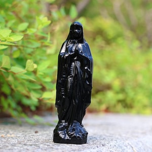 以下が含まれることがあります： 流れるようなローブと手にロザリオを持った、黒い聖母マリアの像です。