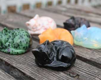 May include: Six sleeping cat figurines made of different types of stone. The cats are in various colors, including green, black, orange, white, and blue.