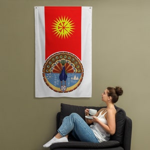 May include: A white flag with a red vertical stripe on the left side. The red stripe features a yellow sun with a stylised cross in the centre. The right side of the flag features a circular design with a peacock in the centre. The peacock is blue and green with a yellow beak and legs. The circle is surrounded by a brown and gold border with various symbols and designs.