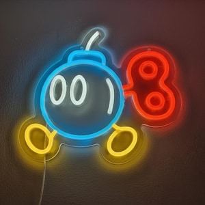 May include: Neon sign depicting a cartoon bomb. The bomb has a blue body, white eyes, and a yellow fuse and base. The key-shaped element is red. The sign is illuminated with neon lights and has a white power cord.
