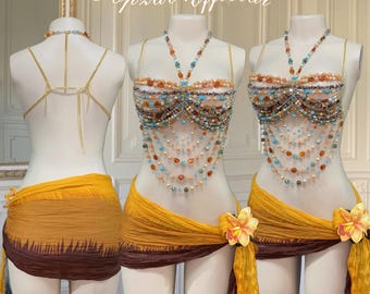 Op de afbeelding: Een kralentop met een gouden ketting en een bijpassende kralenrok. De top en rok zijn beide in tinten oranje, bruin en blauw. De top heeft een gelaagd ontwerp met meerdere kralenstrengen. De rok is een eenvoudige wikkelrok met een bruin en oranje ombre-effect.