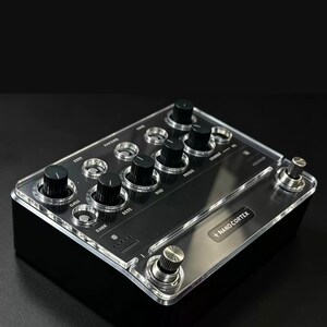 May include: A black Nano Cortex guitar effects pedal featuring a clear acrylic top panel, multiple black rotary control knobs, silver metallic footswitches, and various labeled input and output settings printed on the surface.