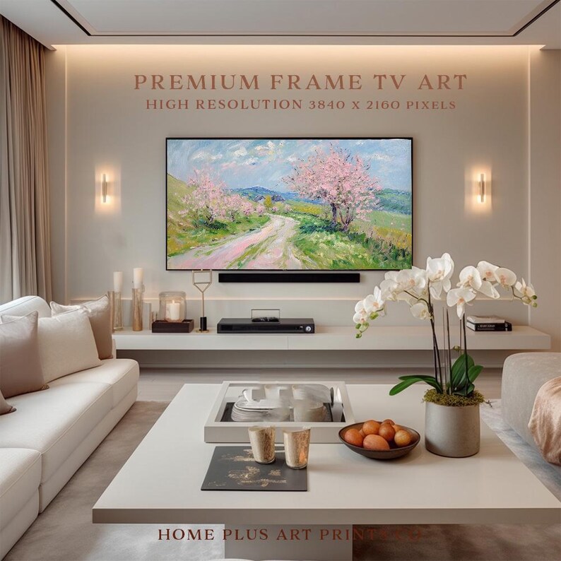 K&ouml;nnte beinhalten: Ein Wohnzimmer-Interieur mit einem wei&szlig;en Sofa, einem Couchtisch und einem gro&szlig;en Flachbildfernseher, der ein Gem&auml;lde eines rosa bl&uuml;henden Baumes und eines gewundenen Weges auf einem Feld zeigt. Der Text "PREMIUM FRAME TV ART HIGH RESOLUTION 3840 X 2160 PIXELS" wird &uuml;ber dem Fernseher angezeigt.