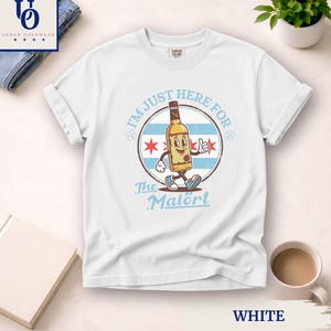 May include: White t-shirt with a cartoon bottle character and the text "I'm Just Here For The Malört." The design incorporates a Chicago flag motif. The shirt is a Comfort Colors brand.