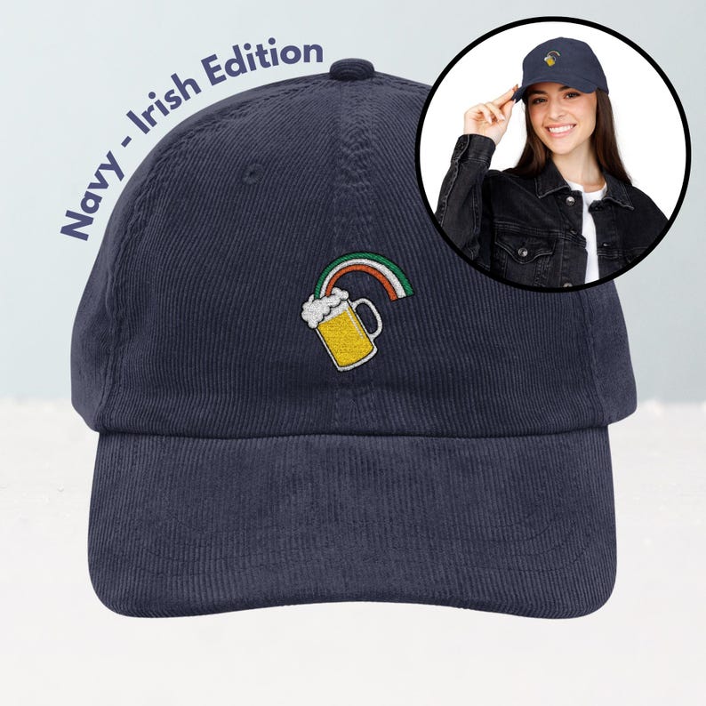 May include: Navy blue corduroy baseball cap with an embroidered design of a beer mug and rainbow. The text "Navy - Irish Edition" is printed on the side of the cap. A woman is wearing a similar cap in a circular inset.