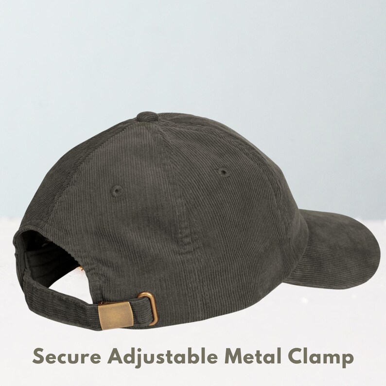 May include: A dark green corduroy baseball cap with a curved brim. The cap features a secure adjustable metal clamp in a gold color on the back for size adjustment. The text "Secure Adjustable Metal Clamp" is visible at the bottom of the image.