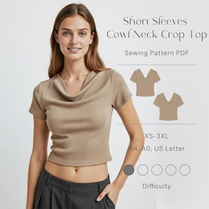 May include: A woman wearing a tan short-sleeved cowl neck crop top. The top is paired with dark gray pants. The image includes text that reads "Short Sleeves Cowl Neck Crop Top Sewing Pattern PDF" and size information.