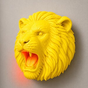 Puede incluir: Una decoraci&oacute;n mural con forma de cabeza de le&oacute;n de color amarillo brillante, con la boca abierta que revela un interior naranja. La melena del le&oacute;n est&aacute; detallada y la escultura est&aacute; montada en una pared gris. La boca abierta tiene un brillo rojo.