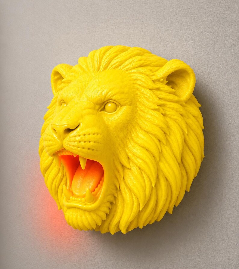 Puede incluir: Una decoraci&oacute;n mural con forma de cabeza de le&oacute;n de color amarillo brillante, con la boca abierta que revela un interior naranja. La melena del le&oacute;n est&aacute; detallada y la escultura est&aacute; montada en una pared gris. La boca abierta tiene un brillo rojo.