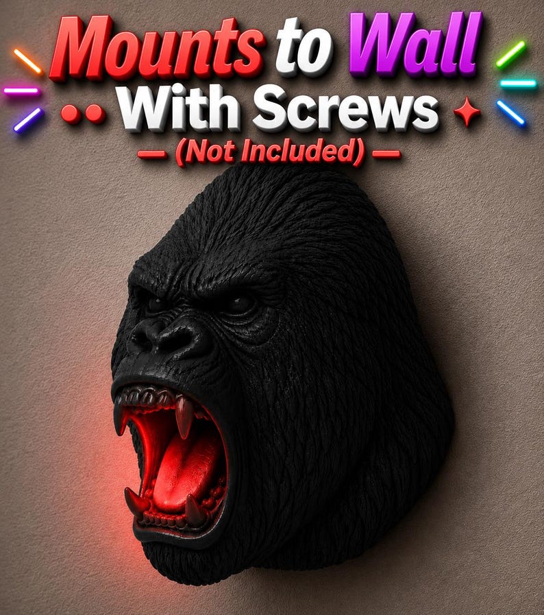 May include: A black gorilla head sculpture with an open mouth revealing red lighting. The sculpture has detailed fur texture and is designed to mount to a wall. The text "Mounts to Wall With Screws (Not Included)" is above the sculpture.