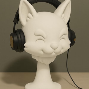 May include: A white, smiling fox head sculpture wearing black headphones with gold accents. The sculpture has a pedestal base and a black headphone cord. The fox has large ears and closed eyes, suggesting a happy expression. The sculpture is on a light-colored surface.