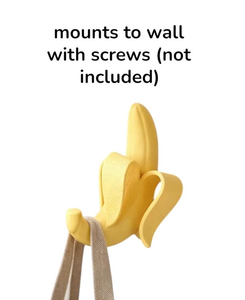 May include: A yellow banana-shaped wall hook with a tan strap hanging from it. The hook is designed to mount to a wall with screws, as indicated by the text "mounts to wall with screws (not included)".