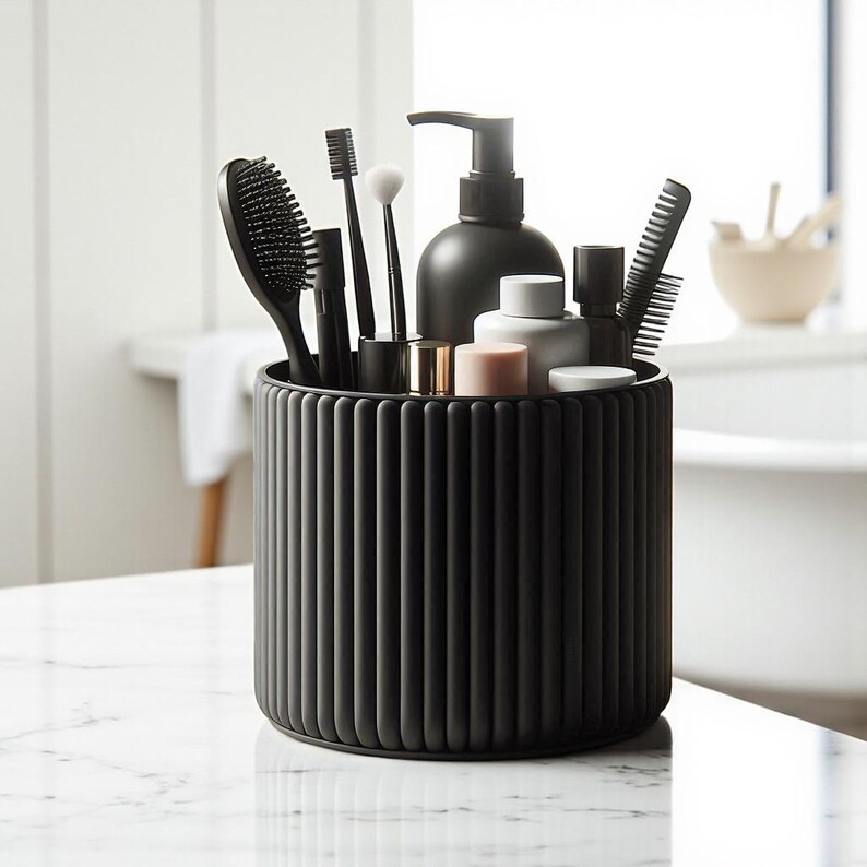 May include: A black, ribbed cylindrical organizer on a marble surface, holding various black bathroom accessories. Items include a hairbrush, toothbrush, makeup brushes, comb, and a soap dispenser. The organizer is filled with toiletries and grooming tools.