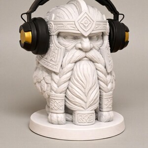 May include: A white statue of a bearded dwarf wearing a helmet and headphones. The headphones are black with gold accents. The dwarf has a long, braided beard and is sitting on a white base.