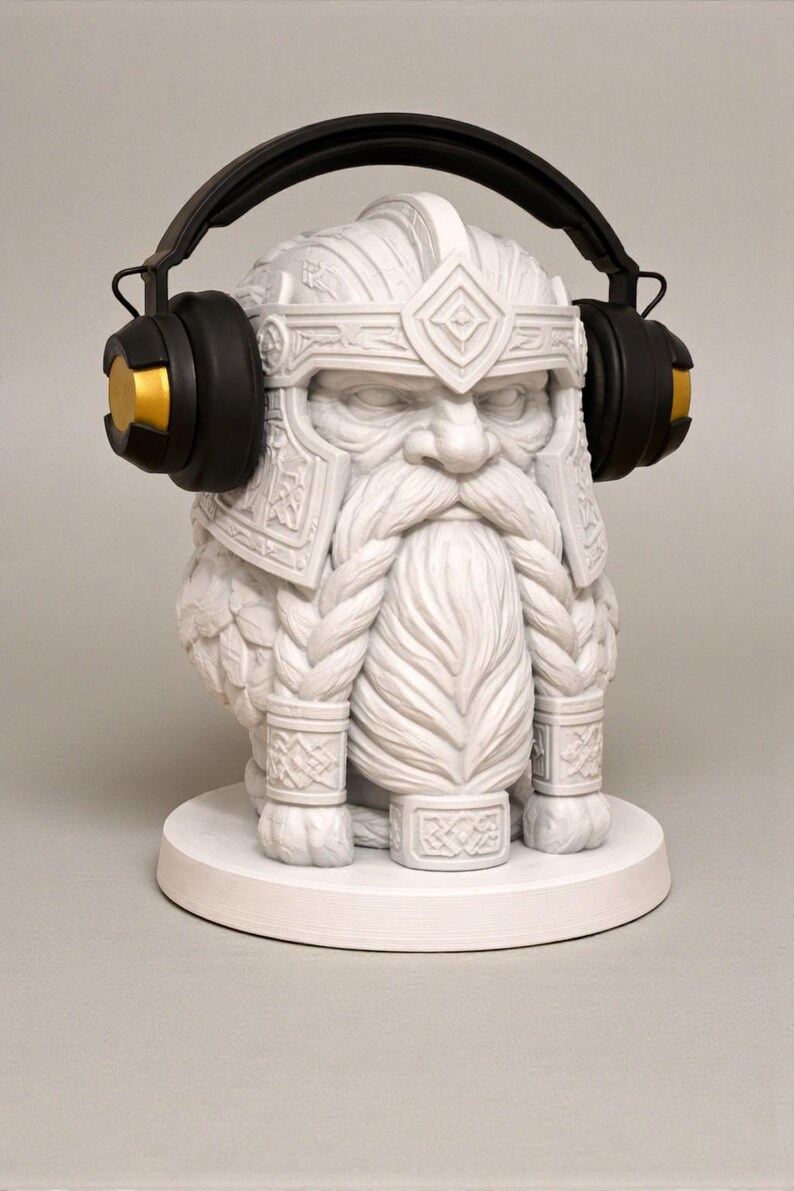 May include: A white statue of a bearded dwarf wearing a helmet and headphones. The headphones are black with gold accents. The dwarf has a long, braided beard and is sitting on a white base.