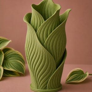 May include: A green, leaf-shaped vase with a textured surface. The vase is designed to resemble a flower bud, with overlapping leaves creating a unique and naturalistic form. The vase is approximately 10 inches tall and is suitable for displaying flowers or as a decorative piece.