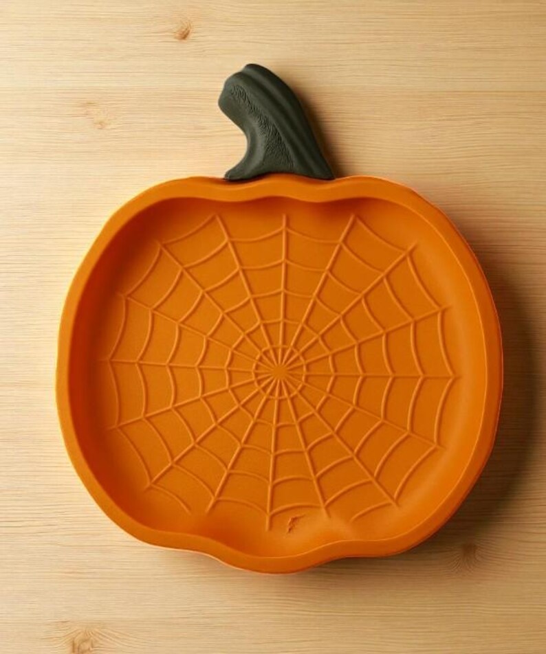 May include: Orange pumpkin-shaped serving dish with a spiderweb design. The dish has a dark green stem and is made of a durable material. Perfect for Halloween or fall-themed gatherings. The dish is approximately 10 inches in diameter.