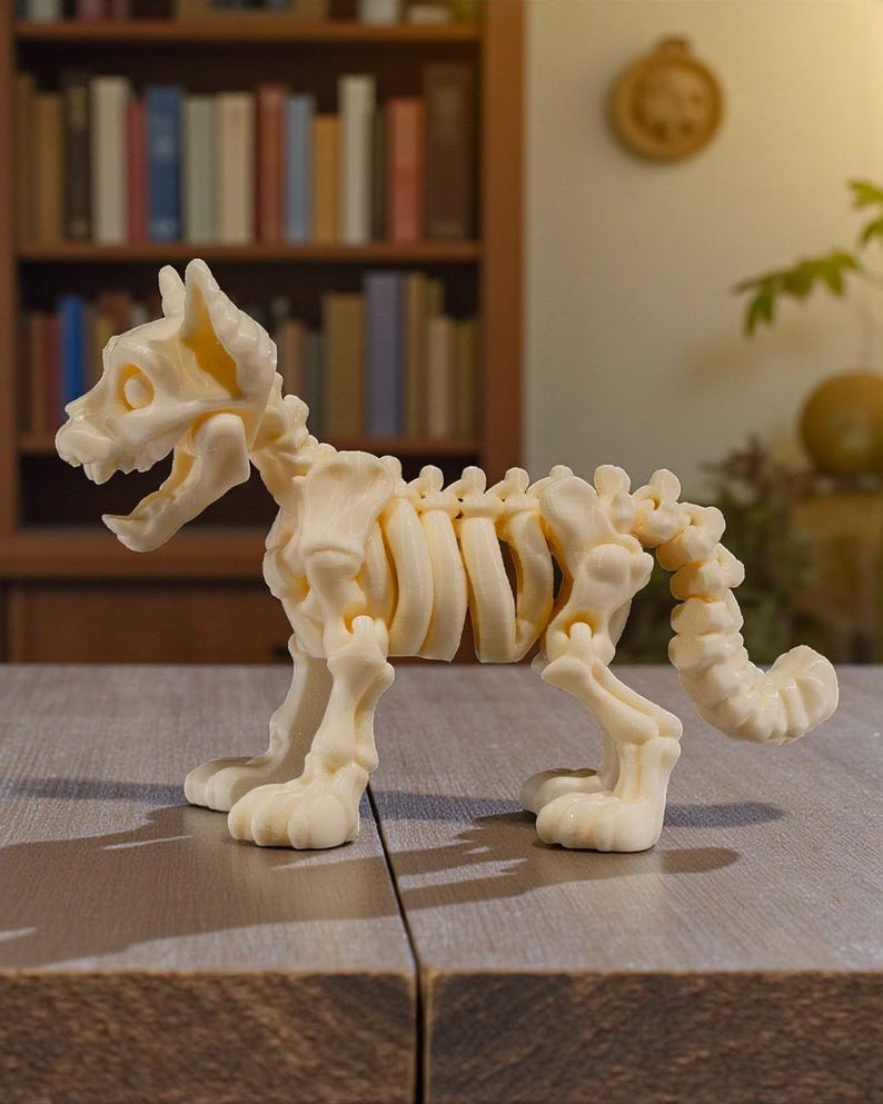 Puede incluir: Figura de esqueleto de perro de color crema con articulaciones articuladas. El esqueleto canino est&aacute; posicionado de pie, con la boca abierta. La figura se exhibe sobre una superficie de madera.