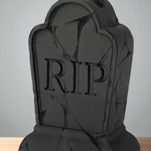 May include: A black tombstone with the letters "RIP" carved into the front. The tombstone has a textured surface and a rounded top. The base is rectangular. The tombstone is a Halloween decoration.