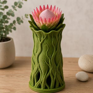 May include: A green vase with a textured, tree-like design, holding a pink and green protea flower. The vase has a wide base and a flared top. The flower has a central, textured pink bloom surrounded by pink petals and green leaves.